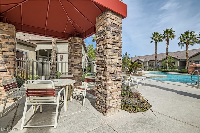 view of patio / terrace featuring a gazebo, outdoor dining area, fence, and a community pool