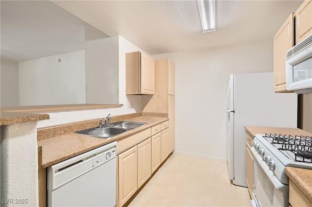 kitchen with light countertops, white appliances, a sink, and baseboards