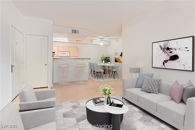 living area with a ceiling fan, visible vents, and light carpet