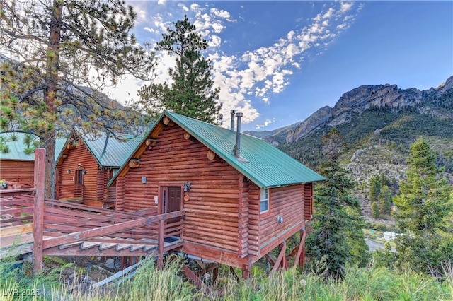 view of side of home featuring a mountain view, metal roof, and log siding