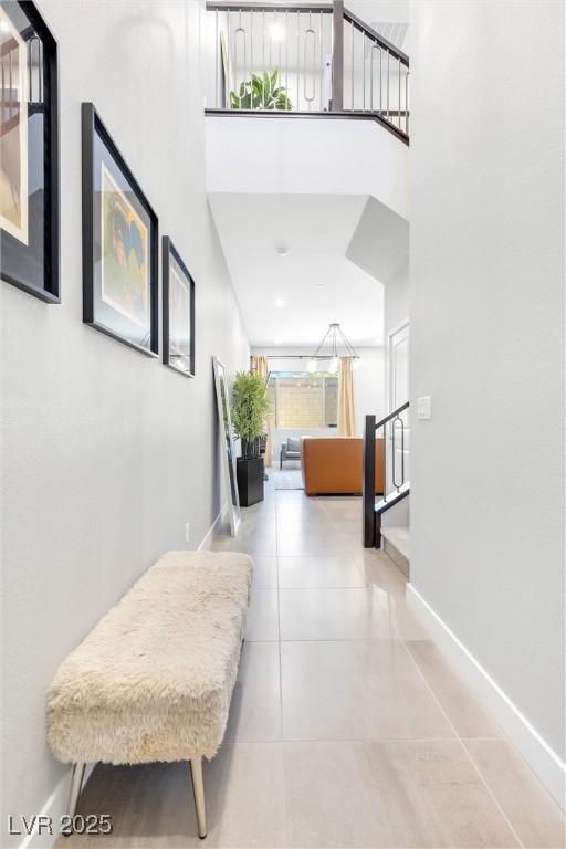 corridor with stairway, tile patterned flooring, and baseboards