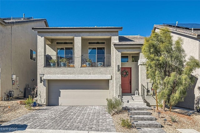 view of front of property with an attached garage, a balcony, central air condition unit, decorative driveway, and stucco siding