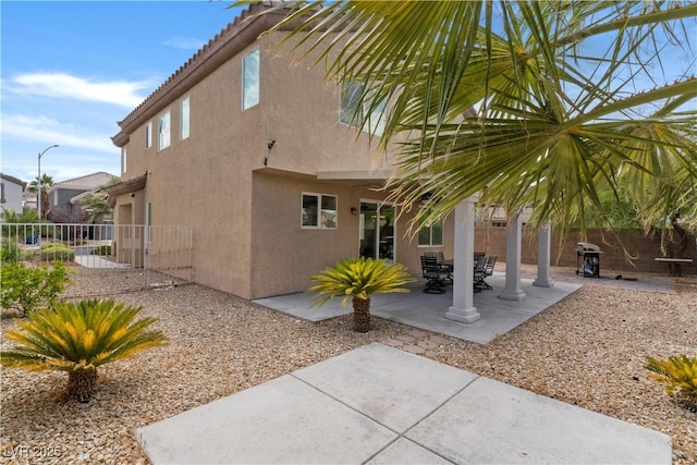 view of side of property with a tile roof, fence, a patio, and stucco siding