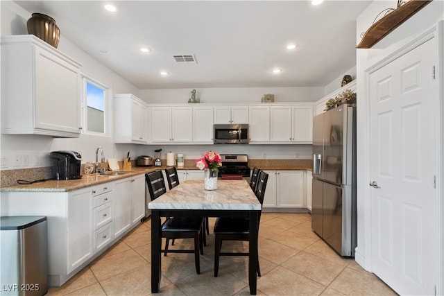 kitchen with visible vents, appliances with stainless steel finishes, white cabinets, a sink, and light stone countertops