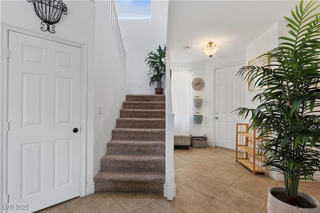 foyer with visible vents, stairway, and light tile patterned floors