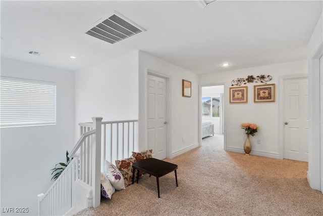 hall with light colored carpet, visible vents, plenty of natural light, and an upstairs landing