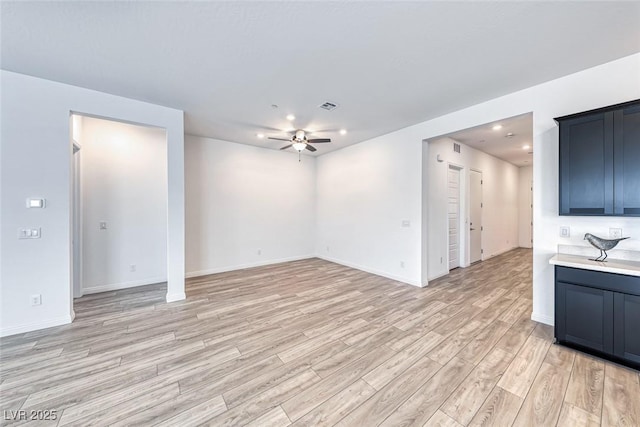 unfurnished living room with ceiling fan, light wood-style flooring, visible vents, and baseboards