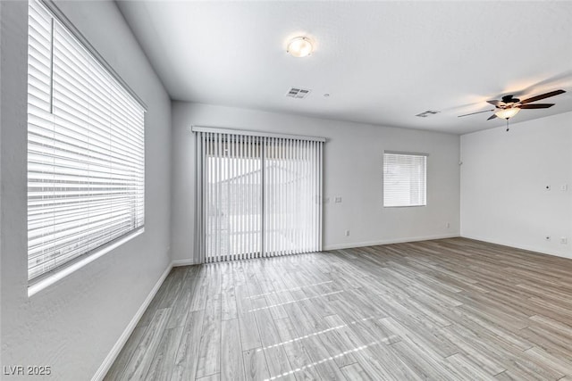 unfurnished room with light wood finished floors, baseboards, and visible vents