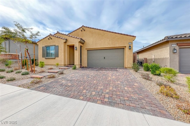 mediterranean / spanish home featuring a garage, a tiled roof, decorative driveway, and stucco siding