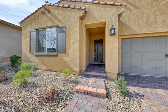 doorway to property featuring a garage and stucco siding