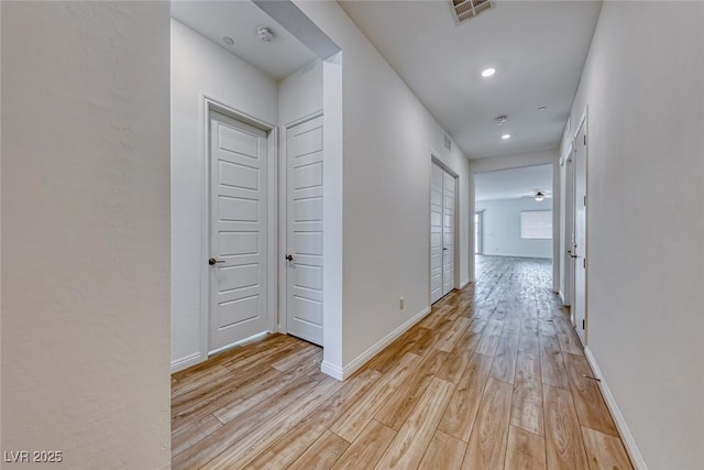 corridor featuring baseboards, recessed lighting, visible vents, and light wood-style floors