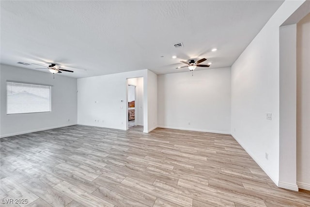 empty room featuring a ceiling fan, light wood-type flooring, and visible vents