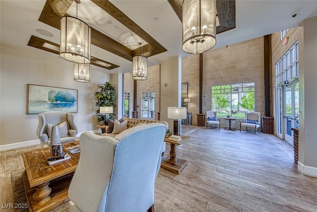 dining area with baseboards, a towering ceiling, brick wall, wood finished floors, and a chandelier