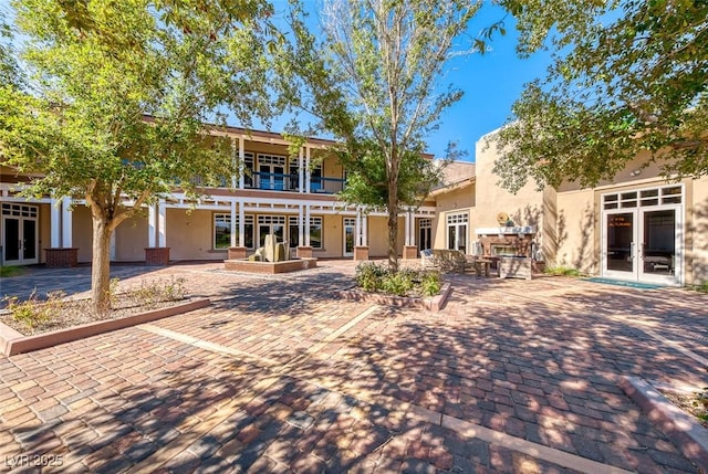 rear view of house with french doors, a patio area, and stucco siding