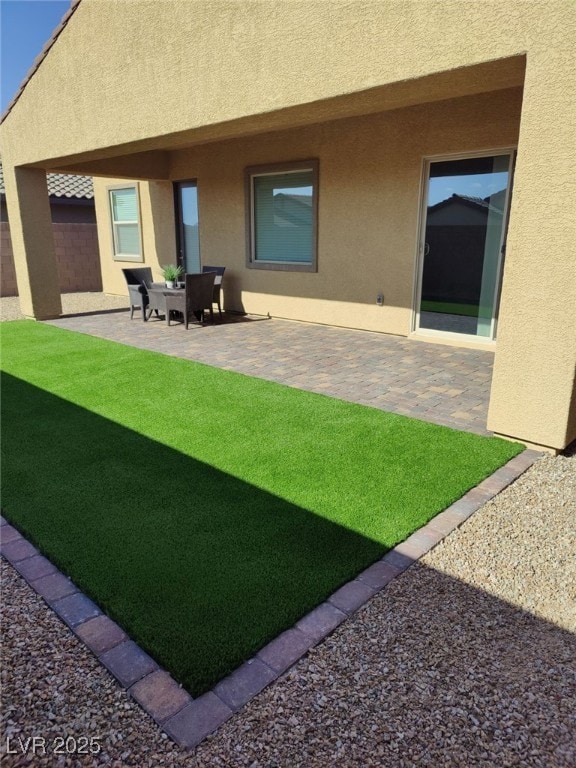 back of house with fence, a patio, a lawn, and stucco siding