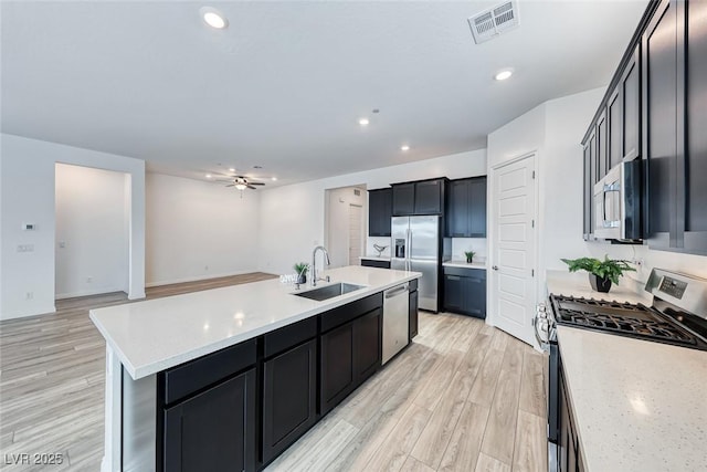 kitchen with visible vents, light wood-style flooring, appliances with stainless steel finishes, a sink, and an island with sink