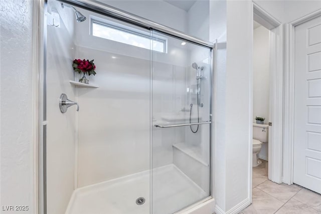 bathroom featuring a stall shower, toilet, and tile patterned floors