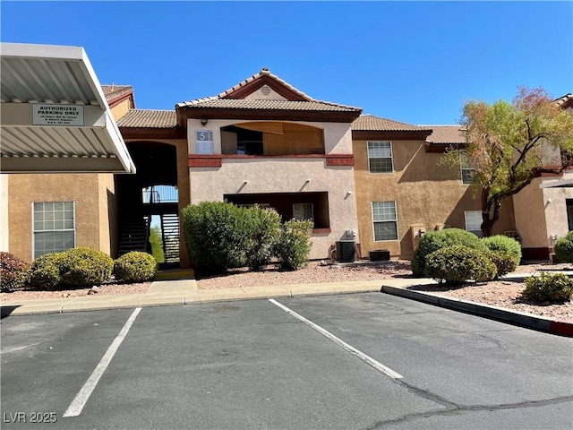 view of property featuring stairs, uncovered parking, and cooling unit