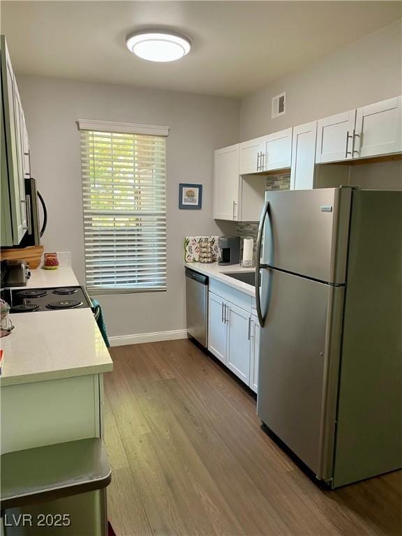 kitchen with stainless steel appliances, visible vents, light wood-style floors, white cabinets, and light countertops