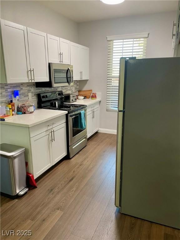 kitchen with stainless steel appliances, light countertops, and white cabinetry