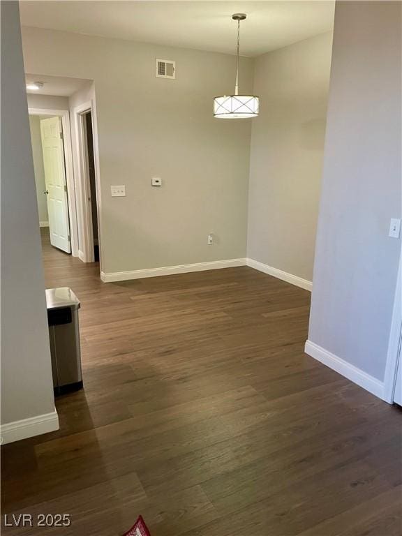 unfurnished dining area featuring baseboards, visible vents, and dark wood-type flooring