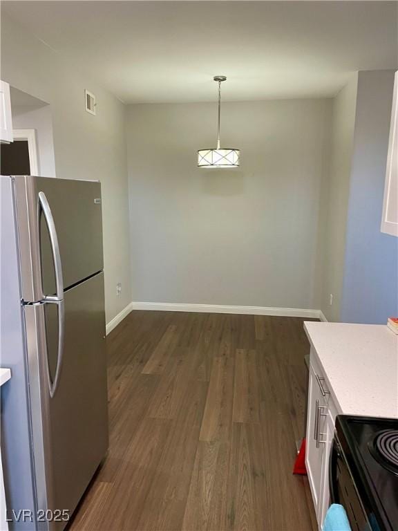 kitchen featuring light countertops, hanging light fixtures, dark wood-type flooring, freestanding refrigerator, and white cabinetry