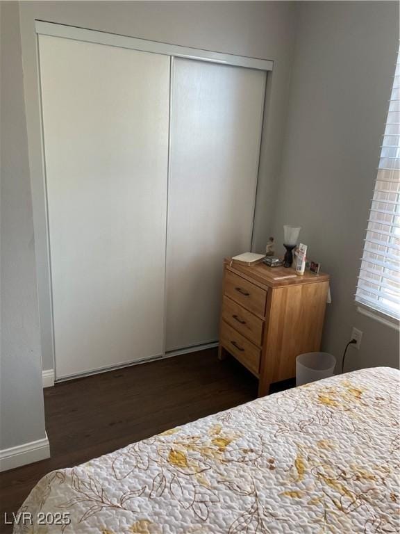 bedroom featuring dark wood-style floors, baseboards, and a closet