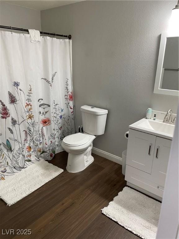 full bath with baseboards, toilet, a shower with curtain, wood finished floors, and vanity