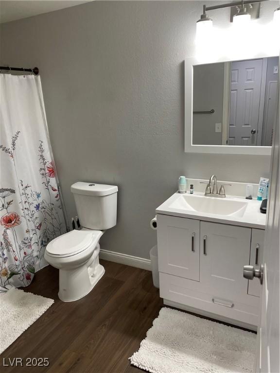 bathroom with baseboards, toilet, wood finished floors, curtained shower, and vanity