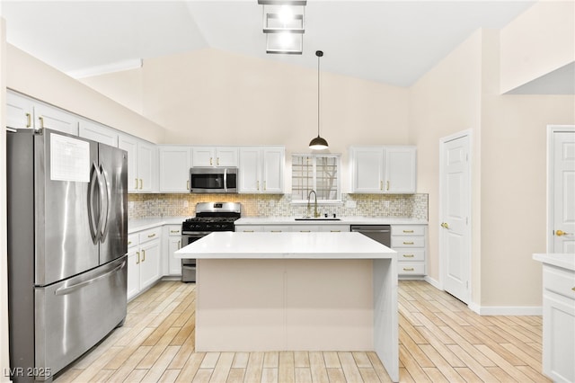 kitchen with light countertops, appliances with stainless steel finishes, decorative light fixtures, and white cabinetry