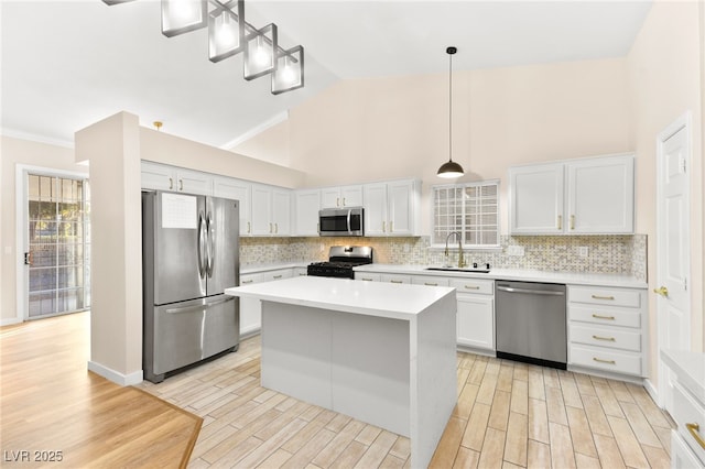 kitchen featuring decorative light fixtures, light countertops, appliances with stainless steel finishes, white cabinets, and a sink