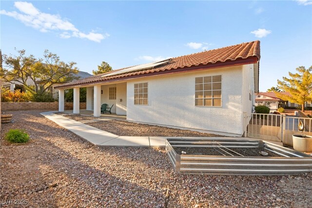 mediterranean / spanish-style home with a tiled roof, a vegetable garden, and fence