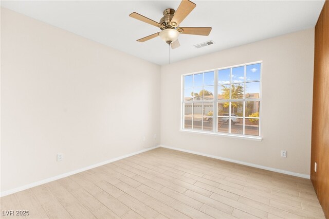 spare room featuring ceiling fan, light wood-style floors, visible vents, and baseboards