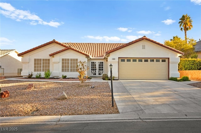 mediterranean / spanish house featuring a garage, a tile roof, concrete driveway, and stucco siding