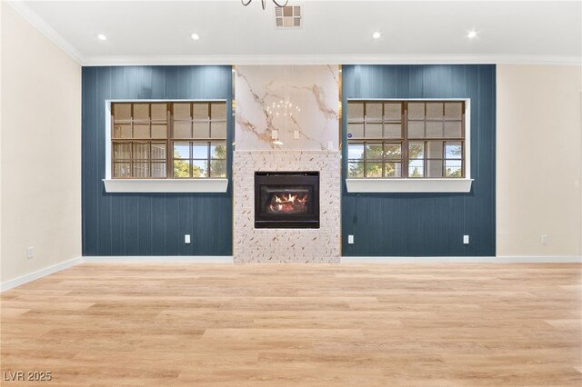 unfurnished living room featuring a fireplace, visible vents, ornamental molding, light wood-type flooring, and baseboards