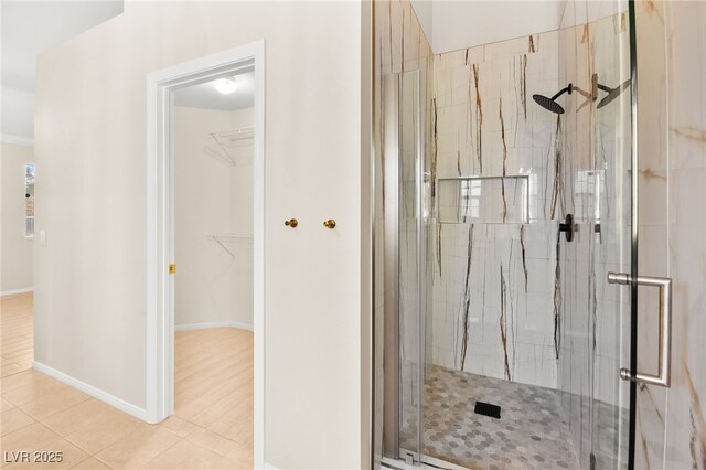 full bathroom featuring tile patterned flooring, a shower stall, baseboards, and a spacious closet