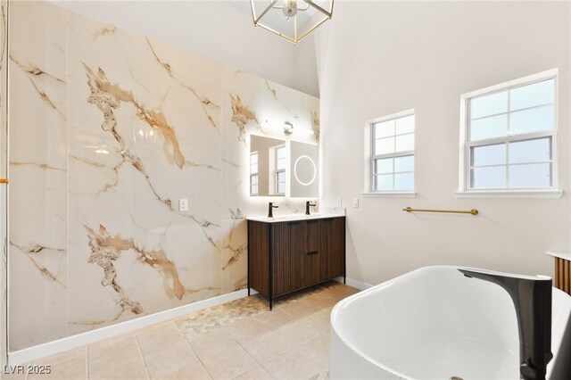 full bath featuring a freestanding bath, baseboards, vanity, and tile patterned floors