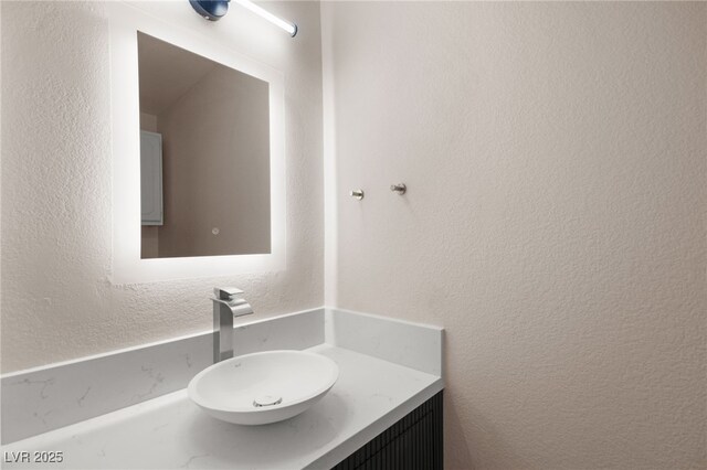 bathroom featuring a textured wall and vanity