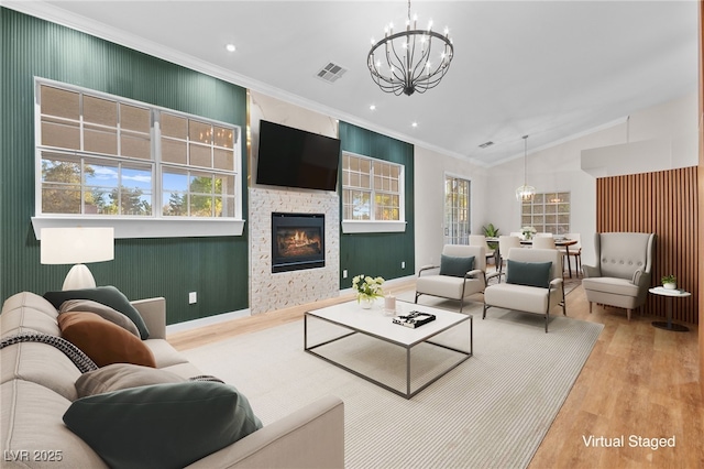 living area with visible vents, lofted ceiling, wood finished floors, crown molding, and a notable chandelier