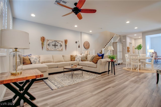 living room with light wood-style flooring, stairway, visible vents, and recessed lighting