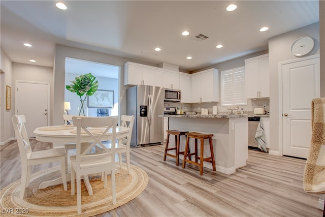 kitchen featuring appliances with stainless steel finishes, light stone countertops, visible vents, and white cabinets