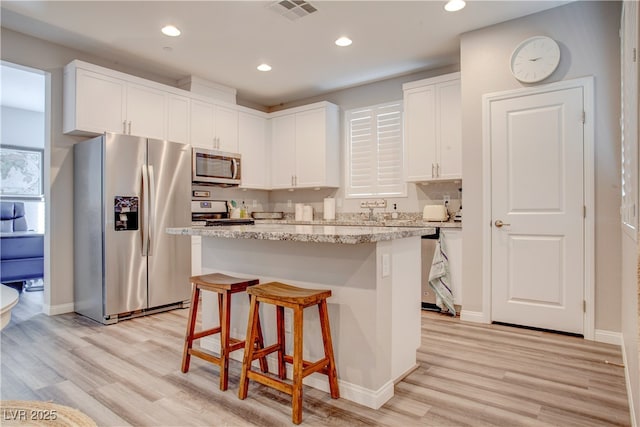 kitchen featuring stainless steel appliances, a center island, visible vents, and white cabinetry