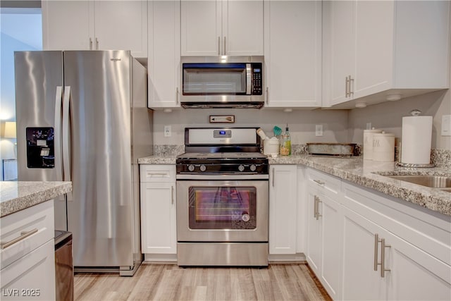 kitchen with white cabinetry, stainless steel appliances, and light stone counters