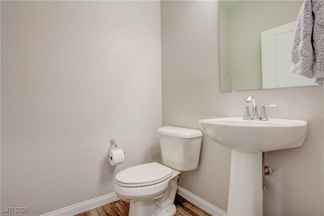 bathroom with a sink, wood finished floors, toilet, and baseboards