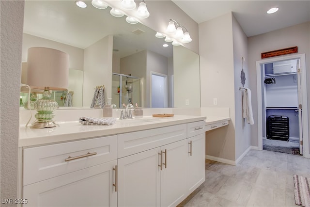 full bath featuring visible vents, vanity, baseboards, a spacious closet, and a stall shower