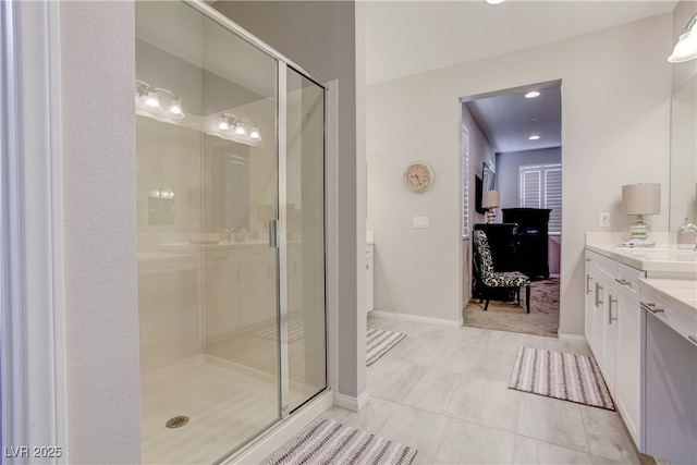 ensuite bathroom featuring a stall shower, baseboards, connected bathroom, and vanity