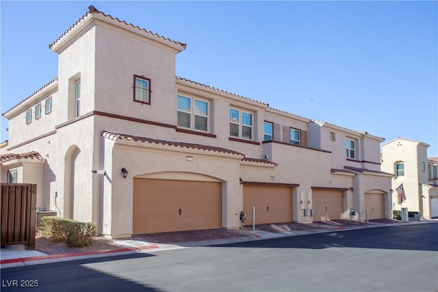 view of front of home with an attached garage, a tile roof, and stucco siding