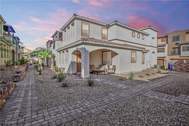 rear view of house featuring a tile roof, a residential view, central air condition unit, a patio area, and stucco siding