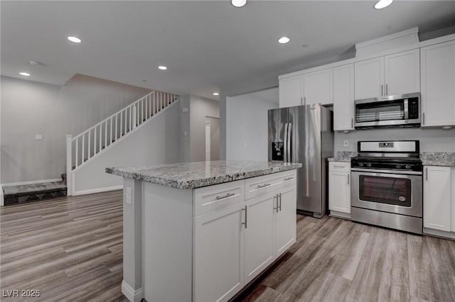 kitchen featuring stainless steel appliances, a kitchen island, light wood-style flooring, and recessed lighting