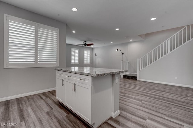 kitchen with baseboards, recessed lighting, light wood finished floors, a ceiling fan, and a kitchen island